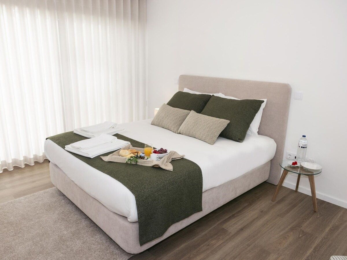 Quarto do apartamento T1 com cortinas de linho e tons verdes