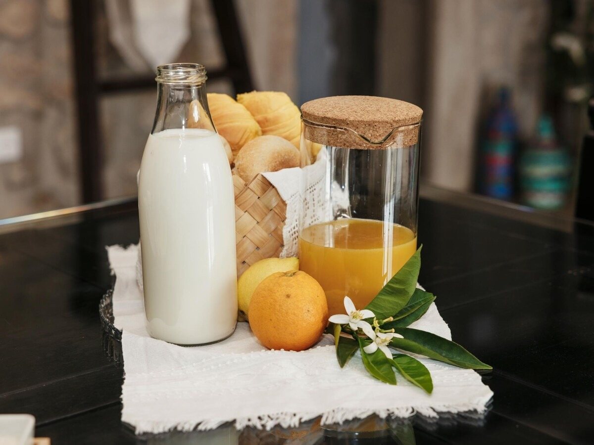 Pequeno-almoço com leite, sumo de laranja, pães e flor de laranjeira